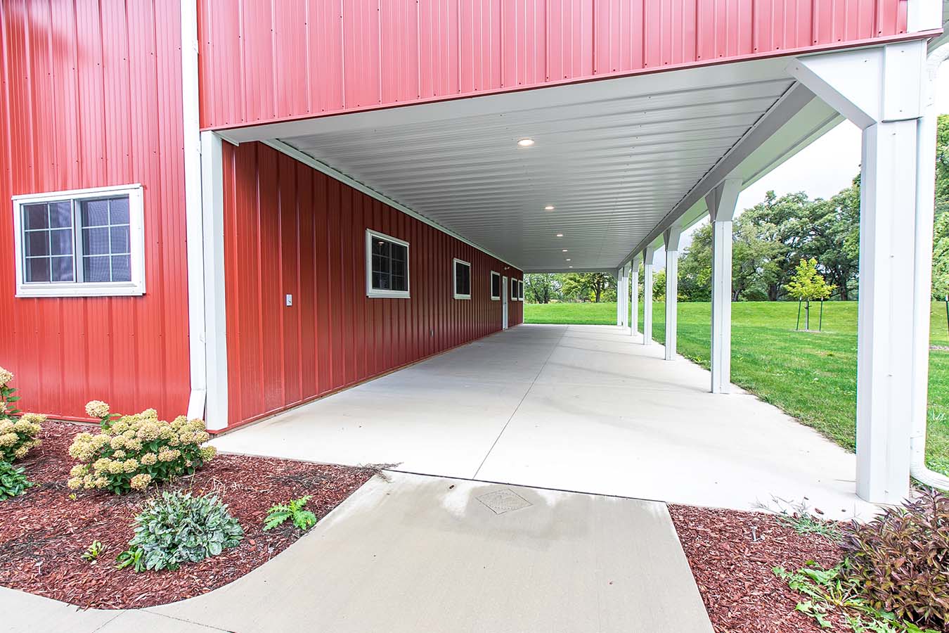 Red pole barn with covered lean-to porch and white support posts