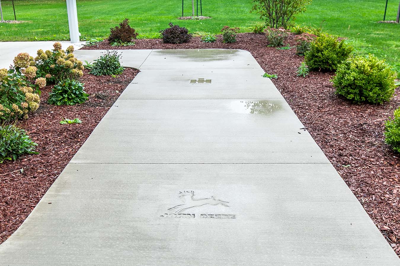 Concrete walkway leading to pole barn with landscaped mulch beds and plants