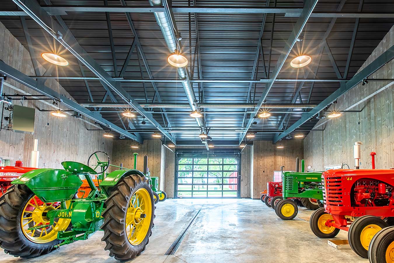 Pole barn interior with vintage tractors, exposed steel trusses, and wood walls