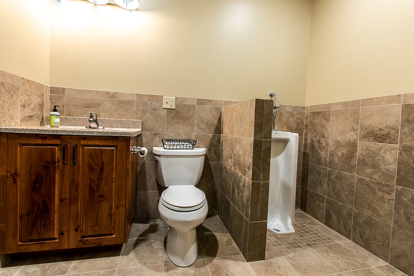 Pole barn bathroom with tile walls, wood vanity, toilet, and urinal