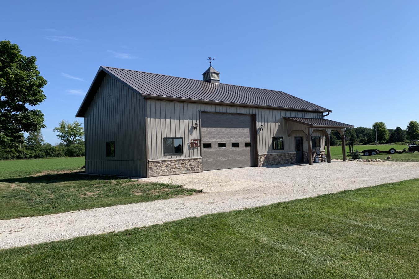 95-1592 Residential workshop with steel siding, stone wainscot, overhead garage door, covered porch, and cupola