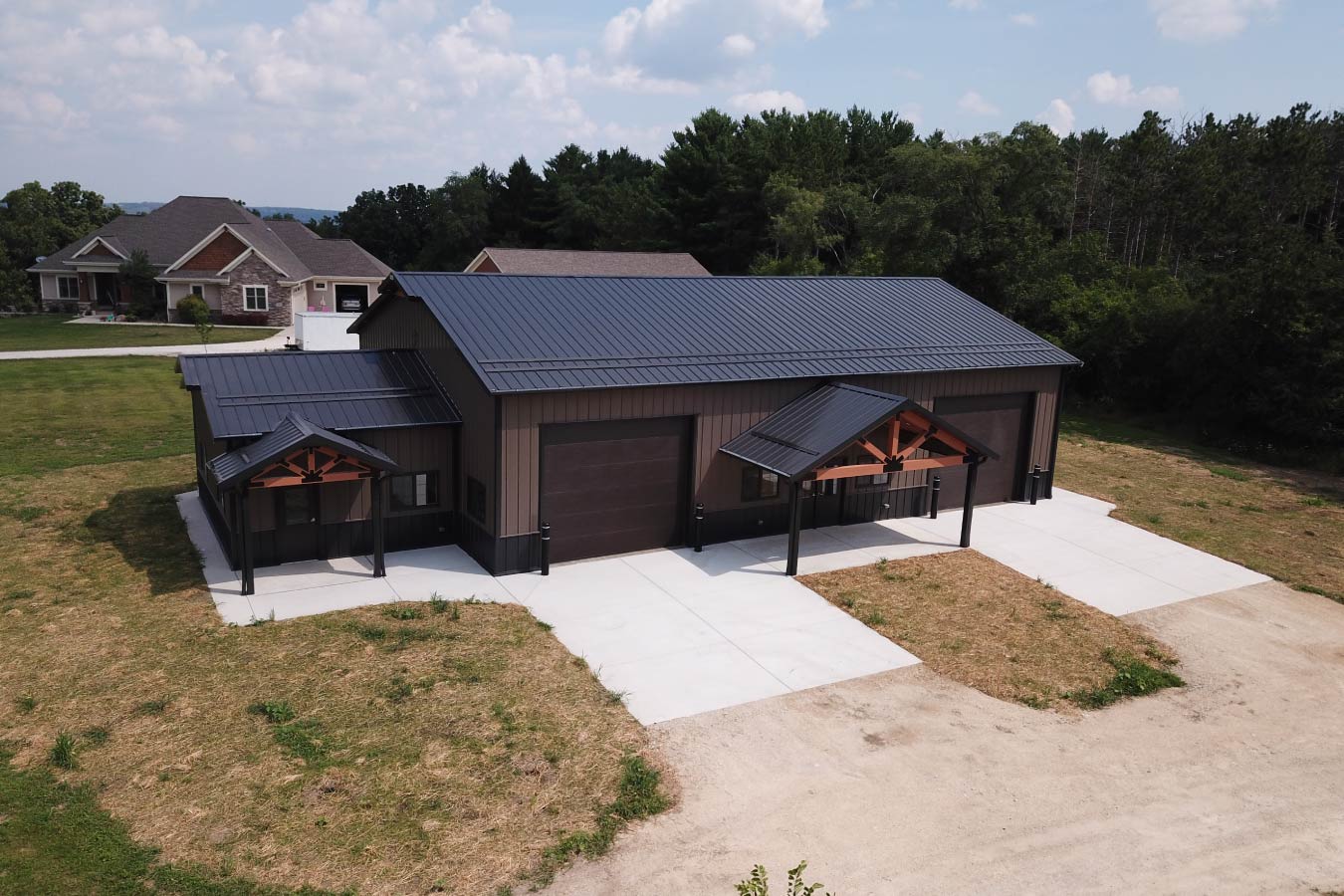 Gable entrance building with steel siding, steel roof, dual overhead doors, and cedar truss entry
