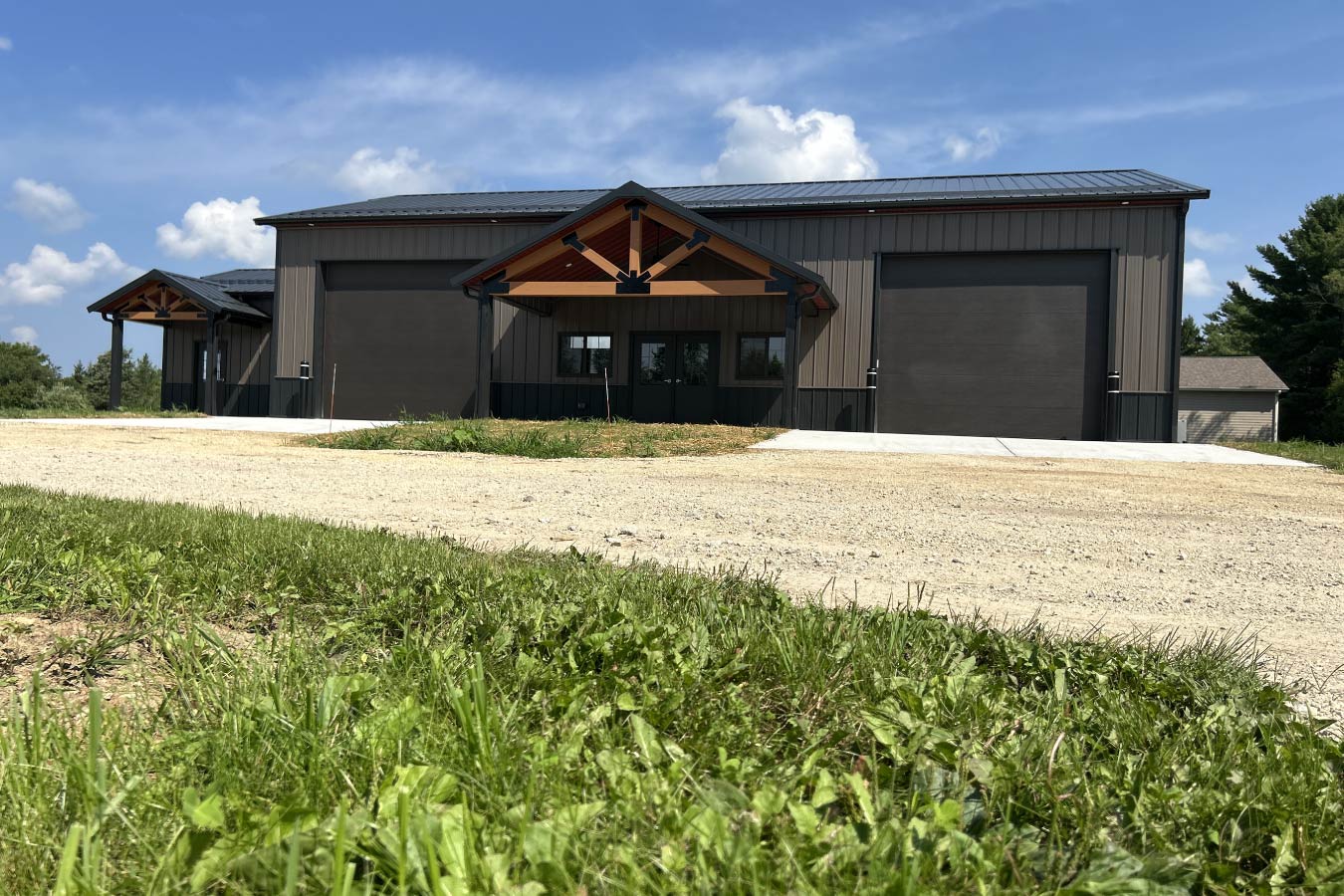 Gable entrance building with steel siding, steel roof, dual overhead doors, and cedar truss entry