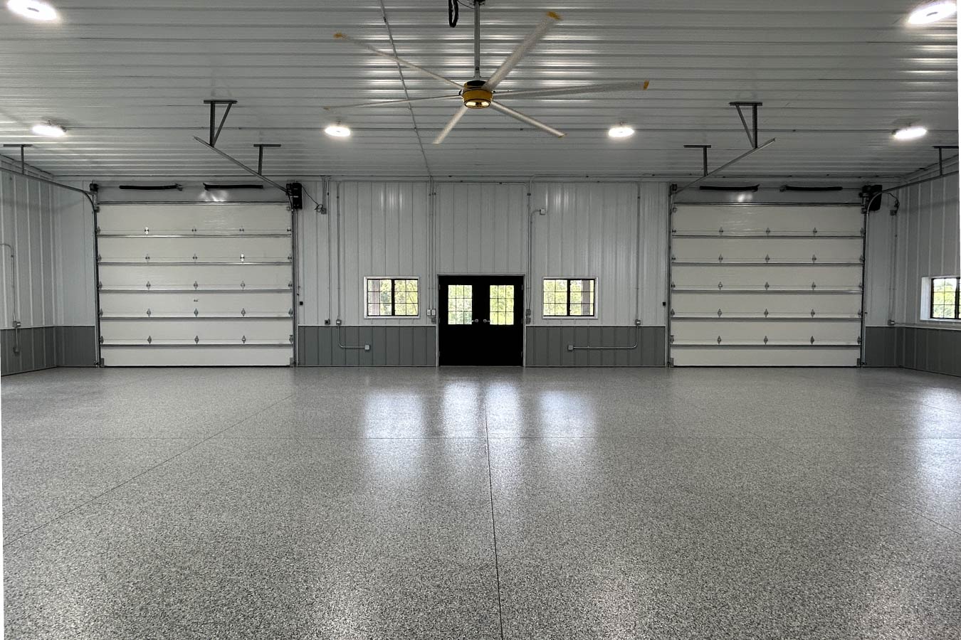 Interior of gable entrance building with epoxy floor, overhead doors, and steel liner panels