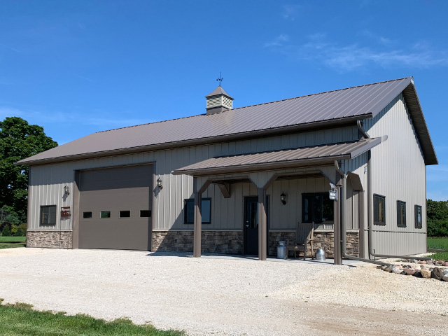 Custom post-frame building in Elkhorn Wisconsin with modern metal siding, large overhead doors, and concrete driveway
