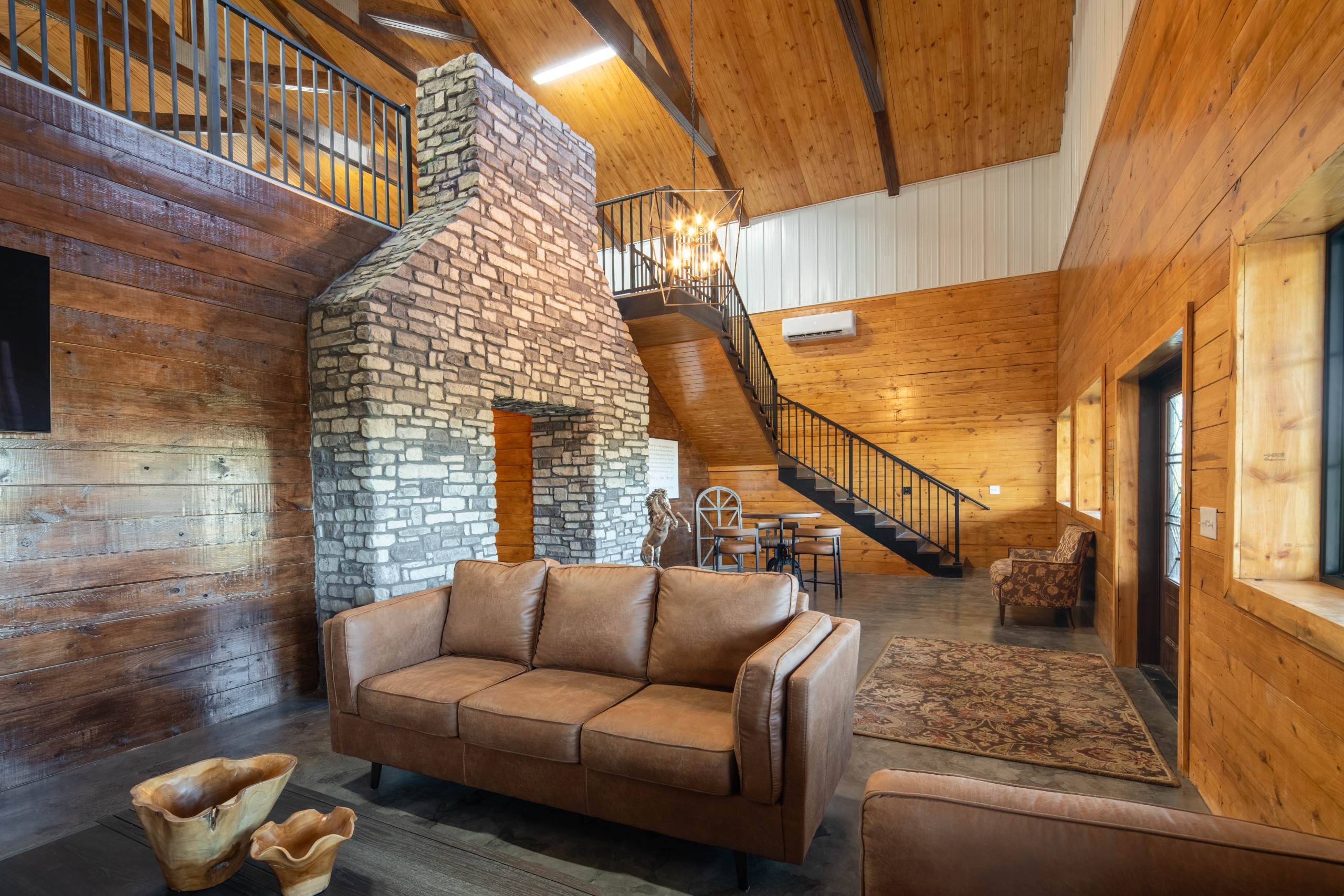 Lobby Lounge and Loft Staircase at The Settlement Equestrian Center Lobby seating area at The Settlement Equestrian Center with stone feature wall, staircase to loft, and warm wood interior finishes