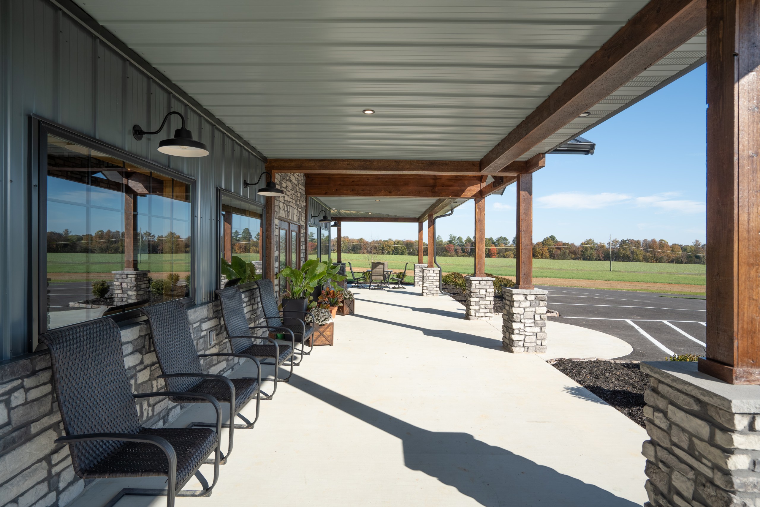 Covered front porch at The Settlement Equestrian Center with seating, stone accents, and views of the surrounding horse property