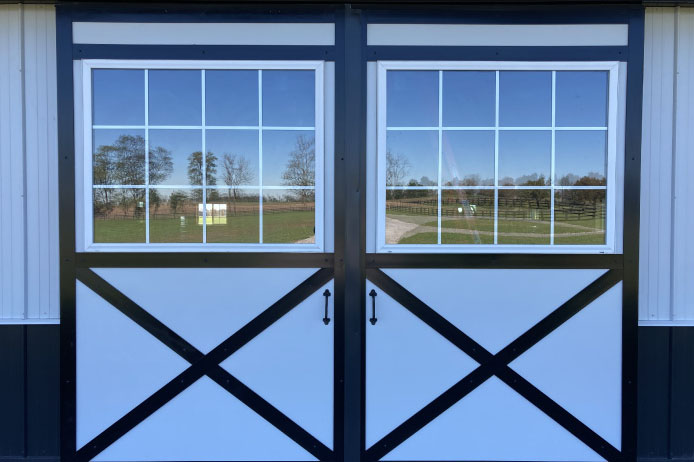 Angled view of 42×63 pole barn with sliding doors, black roof, and gravel driveway Angled view of 42x63 pole barn with sliding doors, black roof, and gravel driveway