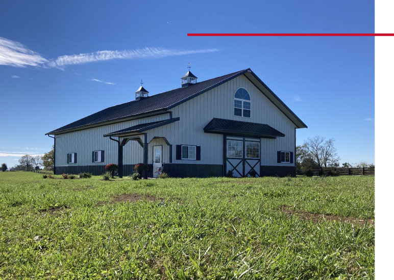 Front view of 42×63 post frame workshop with barn doors, arched window, and covered porch Front view of 42x63 post frame workshop with barn doors, arched window, and covered porch