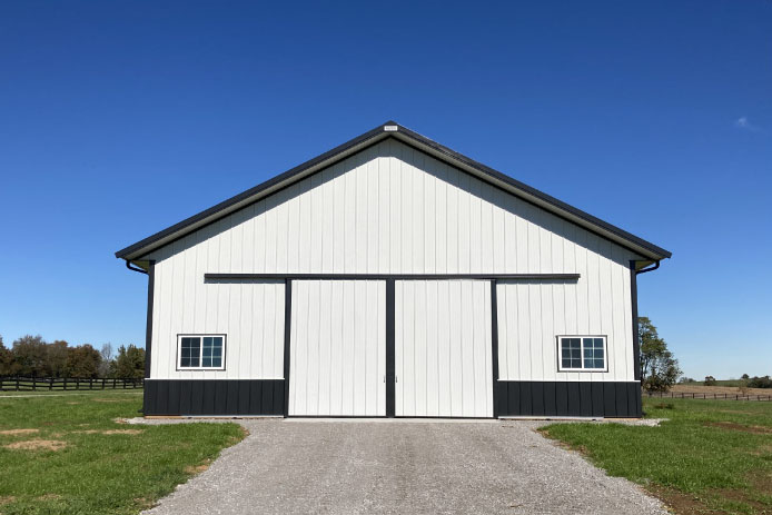 Side view of 42×63 pole barn workshop with black wainscot, metal roof, and covered entry porch Side view of 42x63 pole barn workshop with black wainscot, metal roof, and covered entry porch
