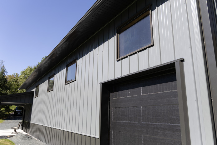 Side view of custom 30×64 post frame garage with cupolas, black roof, and extended covered patio area Side view of custom 30x64 post frame garage with cupolas, black roof, and extended covered patio area