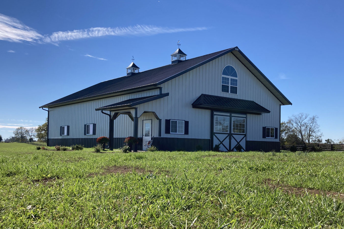 Front view of 42x63 post frame workshop with barn doors, arched window, and covered porch
