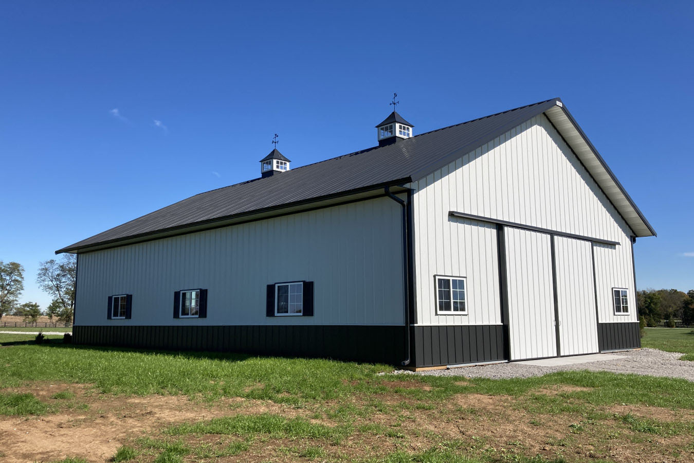 Front-facing view of 42x63 pole barn with wide sliding doors and gravel driveway