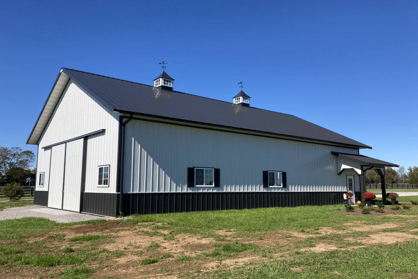 Three-quarter view of 42x63 pole barn with covered porch, barn doors, and black accents