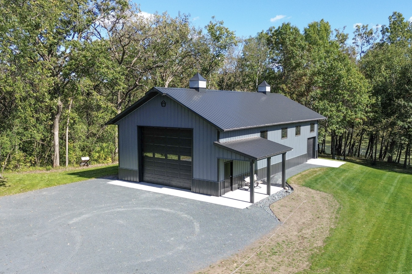 Close-up of 30x64 garage exterior with black overhead door, gray metal siding, and modern trim details