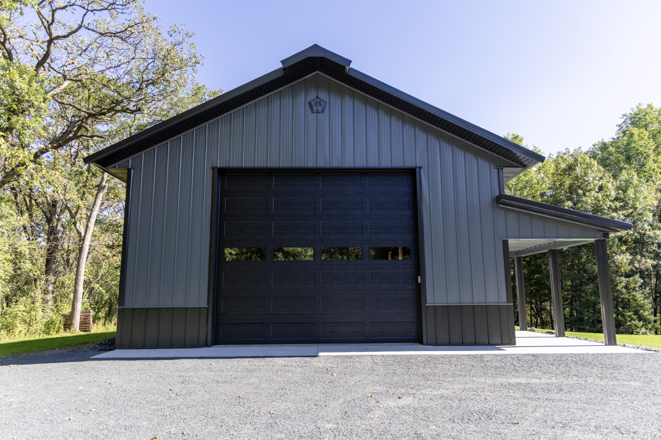 Wide view of custom 30x64 post frame garage with cupolas, black roof, and landscaped green lawn