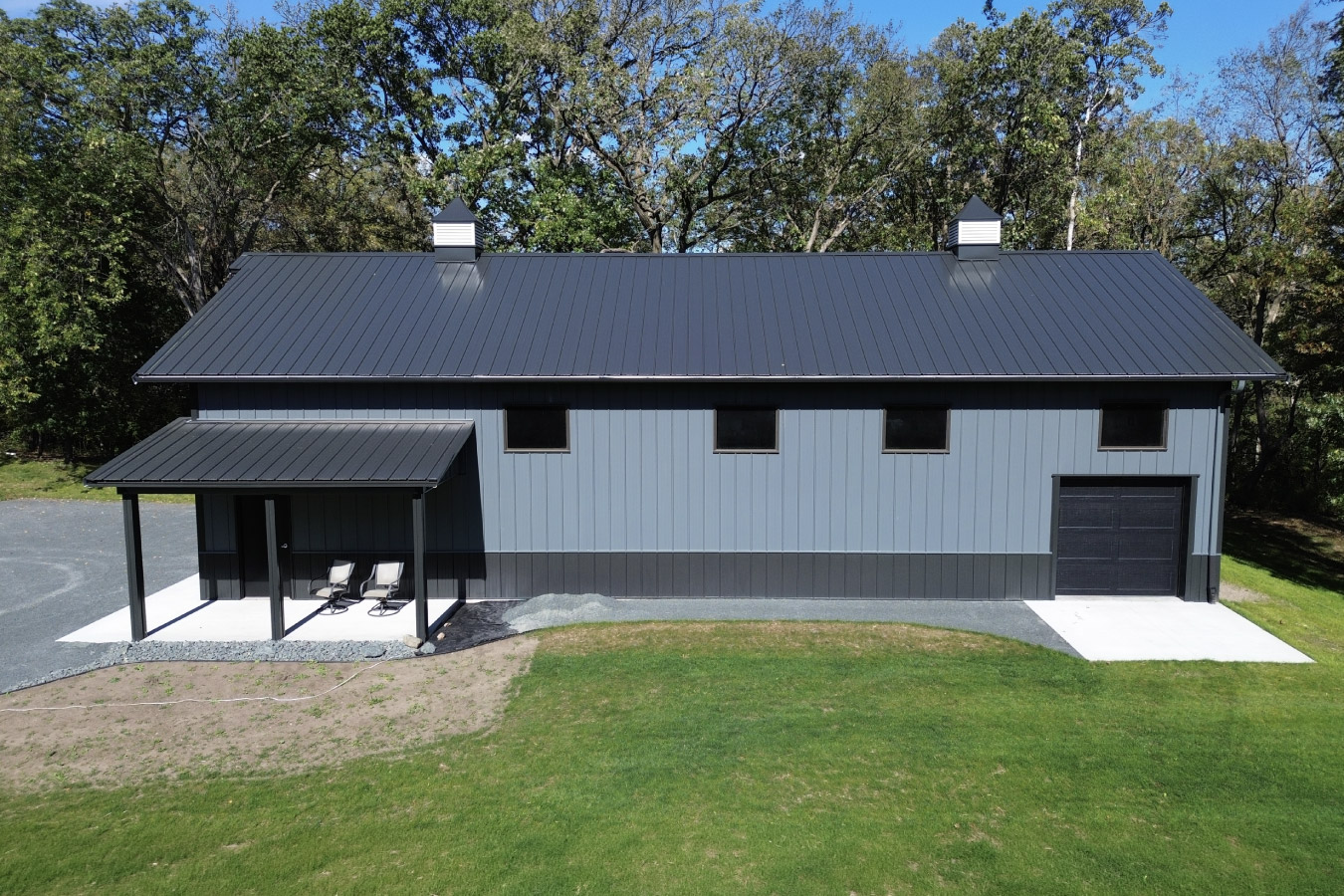 Front elevation of 30x64 post frame garage with large overhead door, gravel driveway, and covered entry
