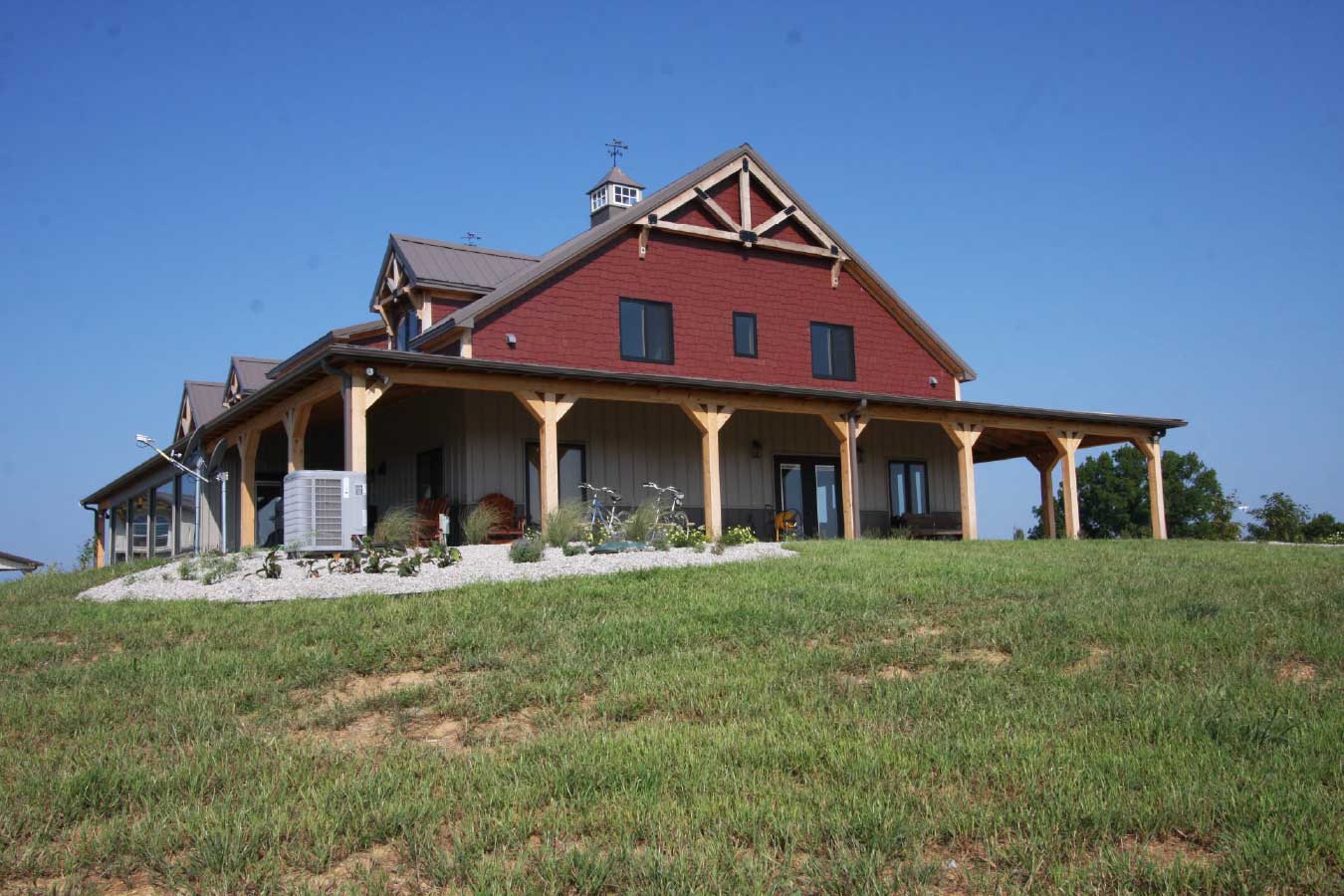 Luxury timber frame home with wraparound porch and decorative gable truss.