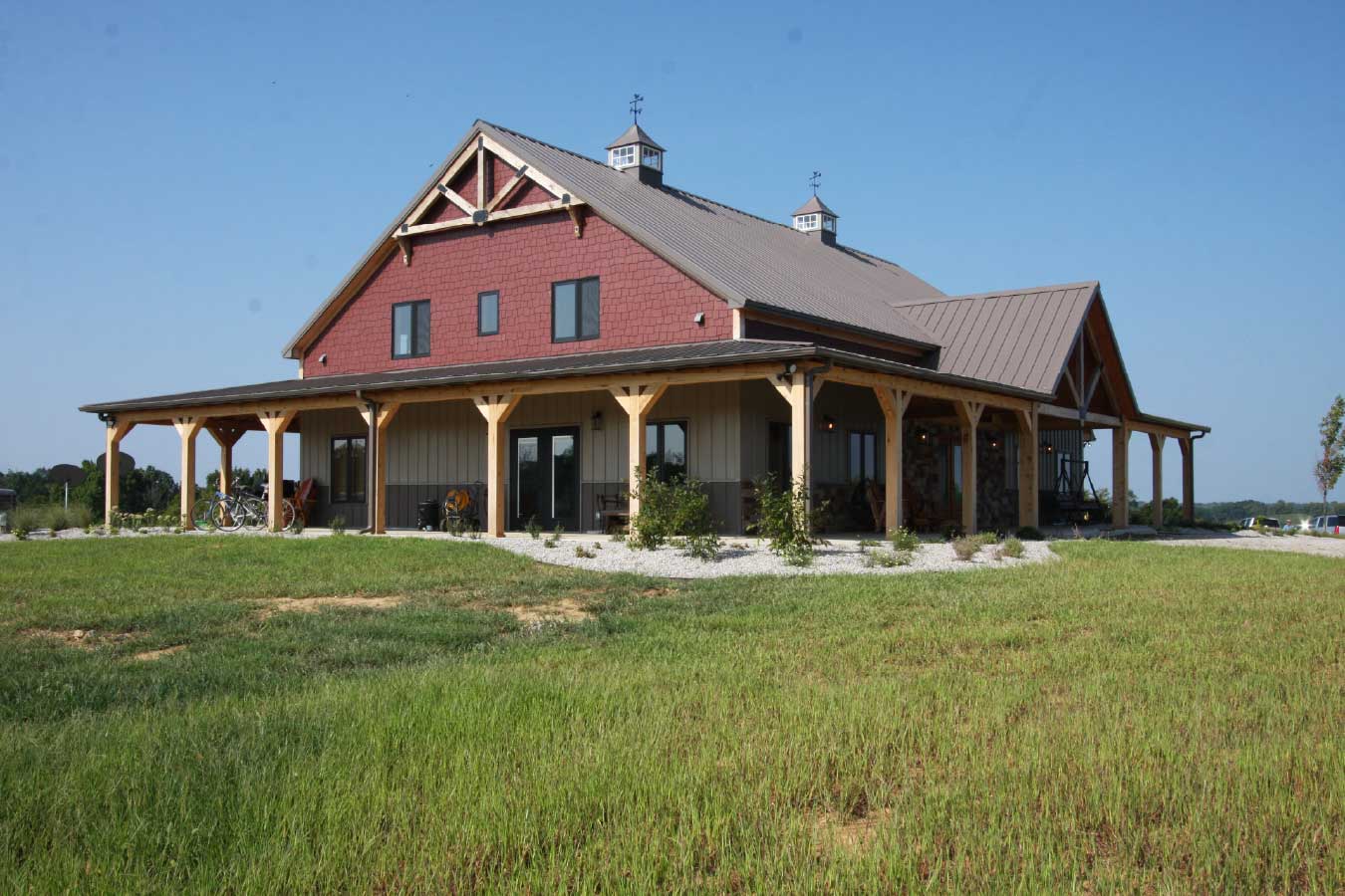 Luxury timber frame home with wraparound porch and shake shingle accents in the front gable.