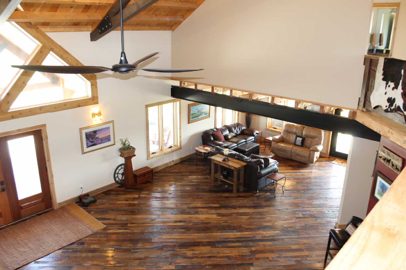 Open-concept living room with vaulted wood ceiling, exposed beam, and loft overlook