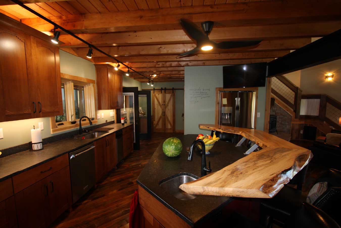 Kitchen inside a luxury timber frame home featuring exposed wood beams, a warm wood ceiling, and custom post-frame residential design.