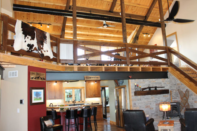 Interior of luxury timber frame home with upper-level space overlooking the living room and kitchen.