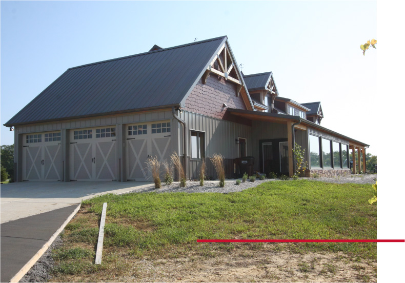 Exterior view of a luxury timber frame home in Kentucky with an attached three-car garage and custom post-frame residential design.