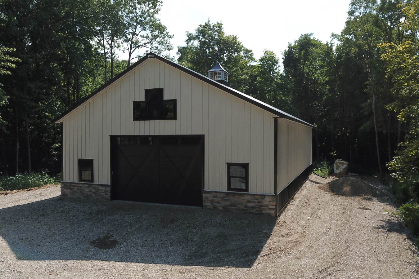 Upper gable window configuration with black trim on white steel-sided post-frame building
