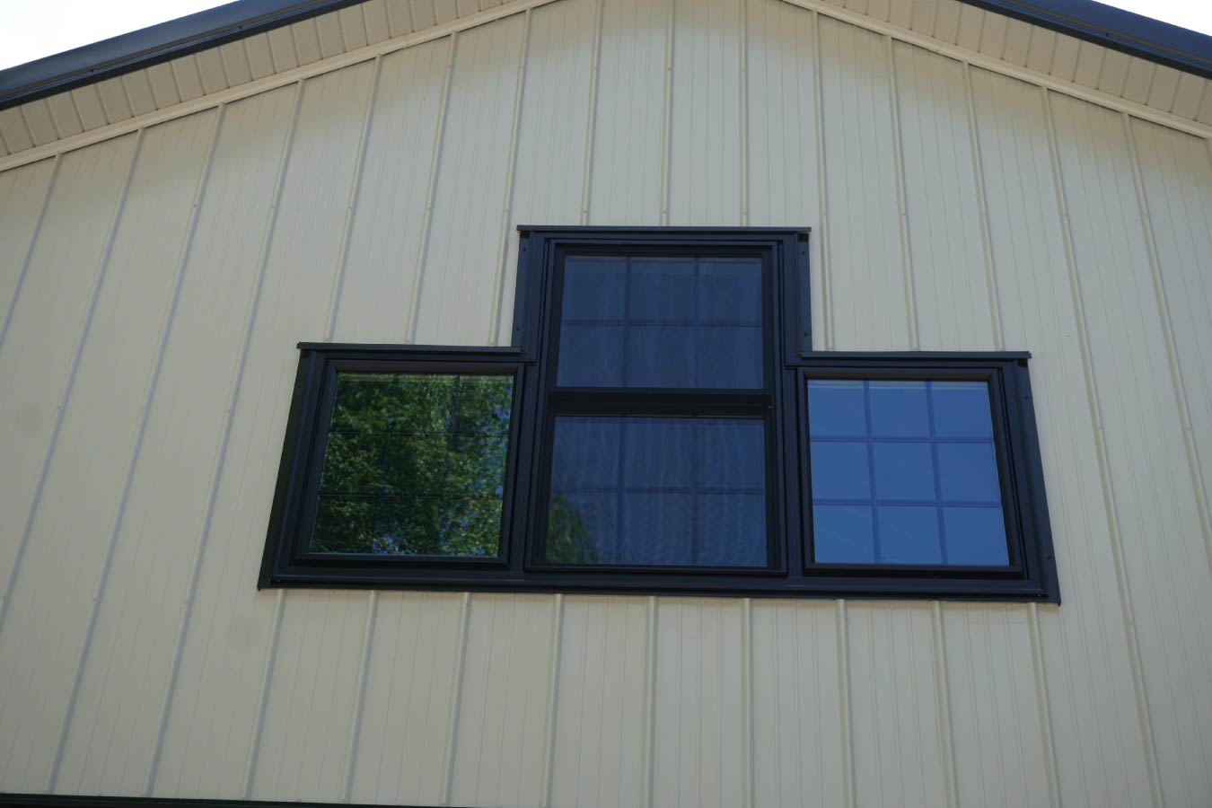 Stone veneer foundation detail on post-frame building corner with metal siding and trim