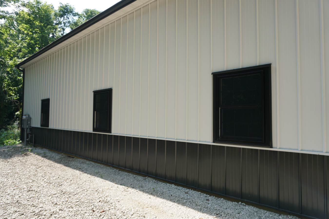 Interior wall detail of post-frame building with wood framing, metal siding, and window bringing in natural light