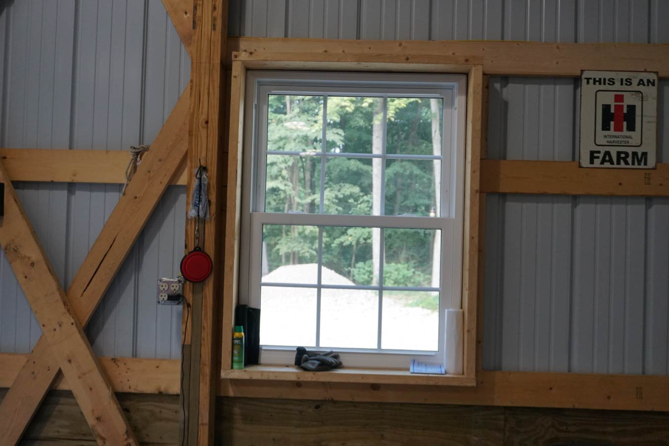 Interior of post-frame building with overhead garage door open to wooded property and concrete floor workspace