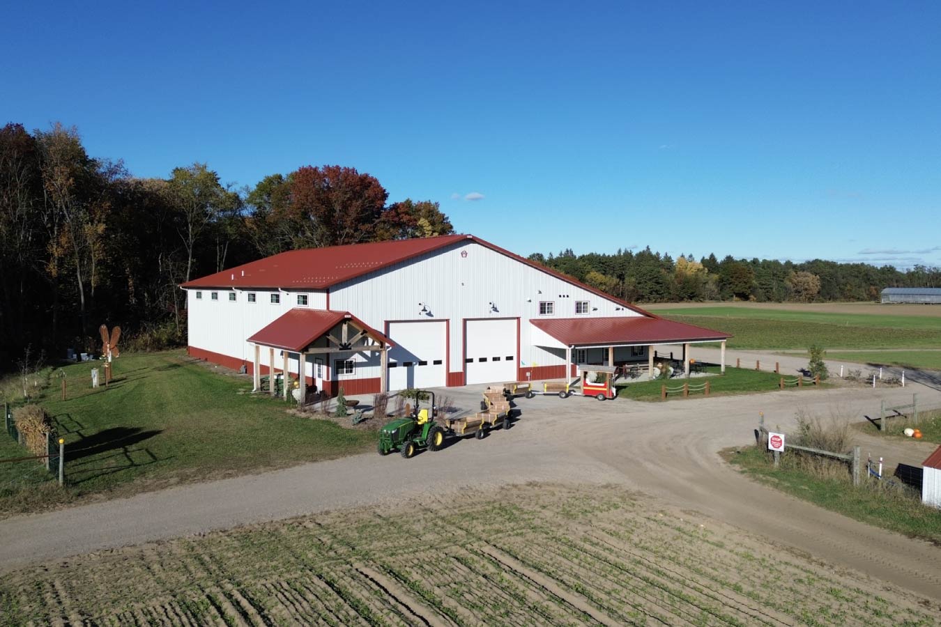 Angled exterior view highlighting covered entry, large overhead doors, and integrated farm market and storage spaces