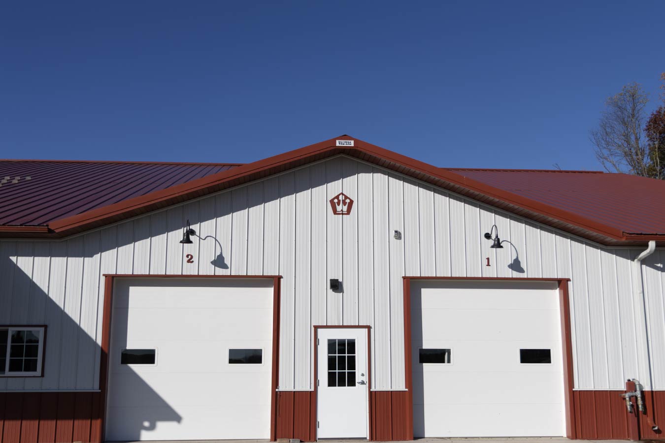 Exterior detail of upper wall with evenly spaced windows, white steel siding, and red trim beneath roofline