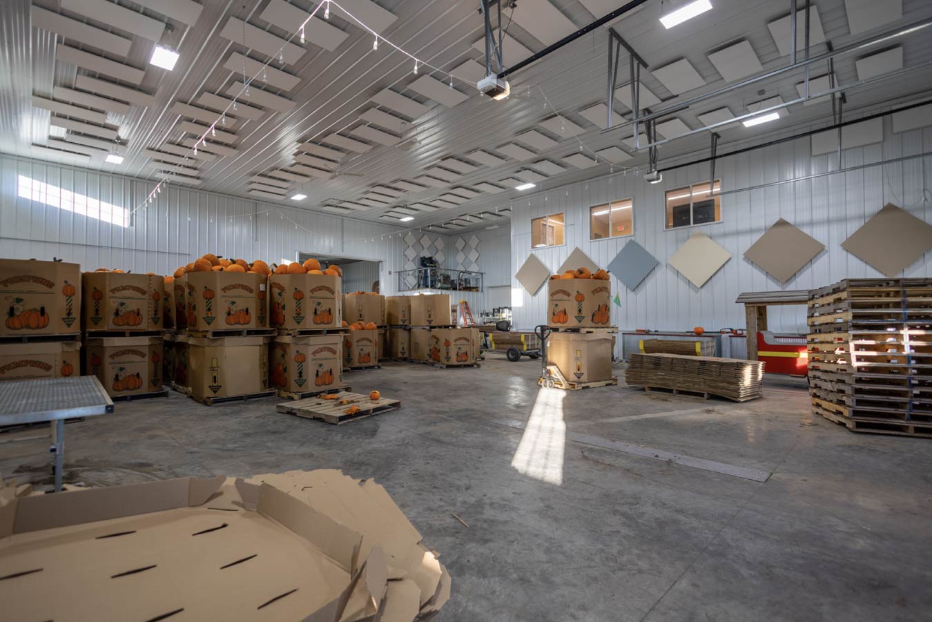 Large post-frame interior with overhead garage doors, high ceilings, bright lighting, and open workspace for equipment and fabrication