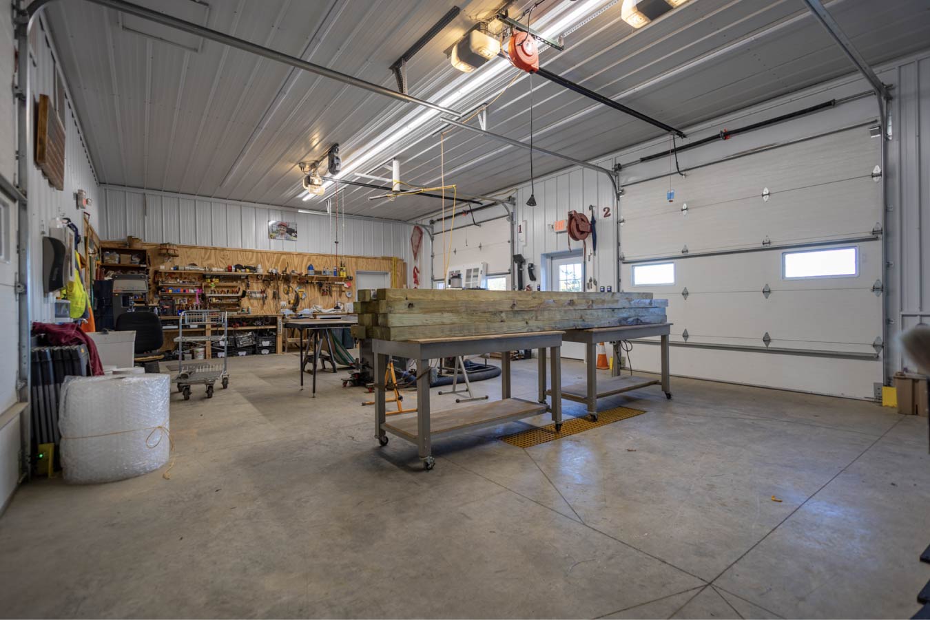 Interior workshop area with organized tool wall, wood-lined lower walls, workbenches, and mounted storage for equipment and supplies