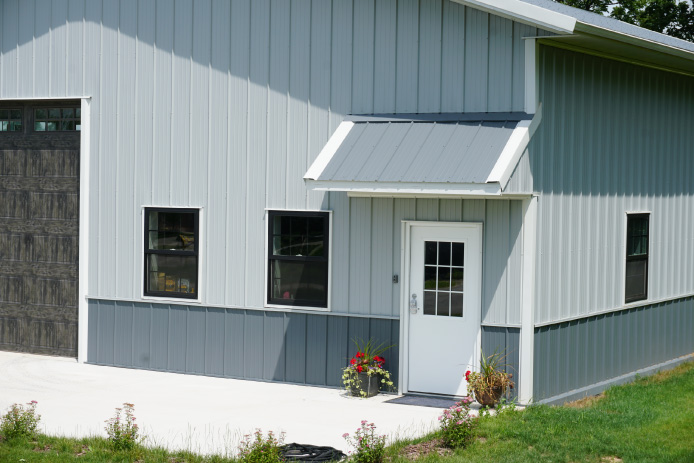 40×60 Pole Barn Garage with Entry Awning and Black Windows | Walters Buildings 40x60 custom pole barn garage with white steel siding, charcoal wainscot, entry awning, and black windows