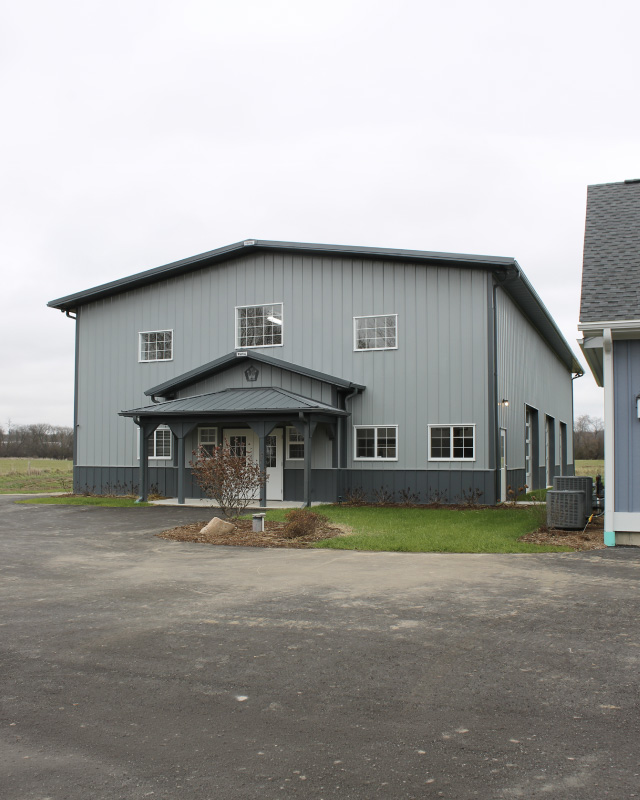 Indoor basketball court building with gray steel siding and custom post frame construction