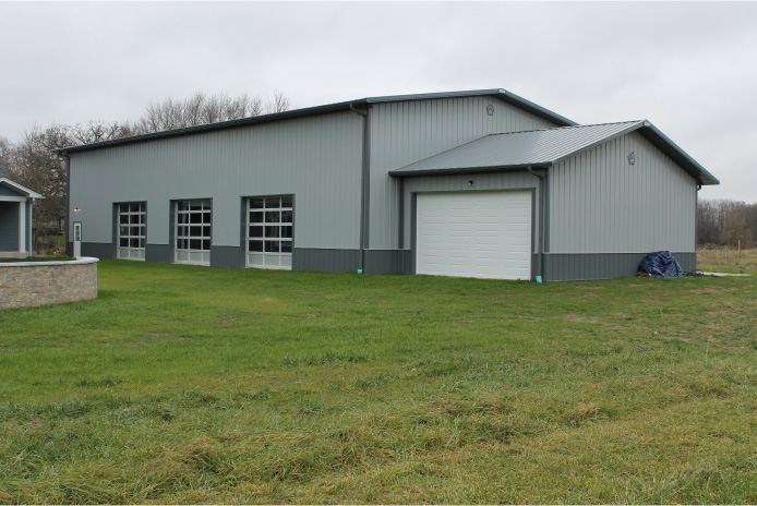 Large indoor sports building with gray steel siding multiple overhead doors and clear-span post frame construction