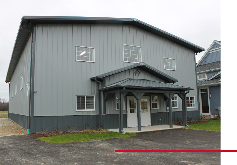 Private indoor basketball court building with gray steel siding and custom post frame sports facility design