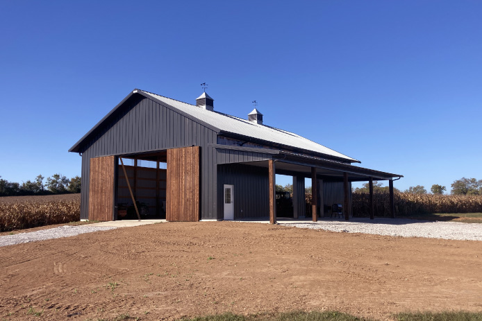40×64 Pole Barn with Sliding Barn Doors and Lean-To | Walters Buildings 40x64 pole barn with black steel siding, wood sliding barn doors, open bays, and covered lean-to