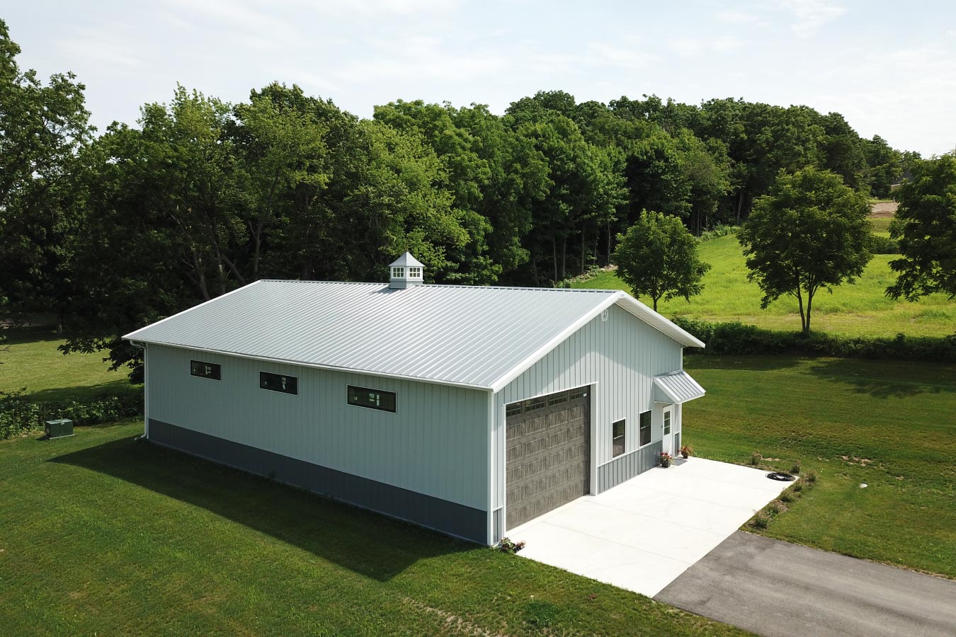 Project #94-0603 40x60 backyard pole barn garage with white steel siding, charcoal wainscot, cupola, and overhead garage door