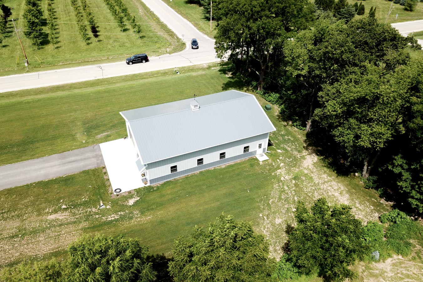 40x60 backyard pole barn garage with white steel siding and gray roof shown from aerial view
