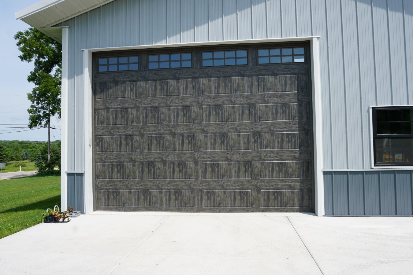 40x60 pole barn garage with oversized wood grain overhead garage door and white steel siding