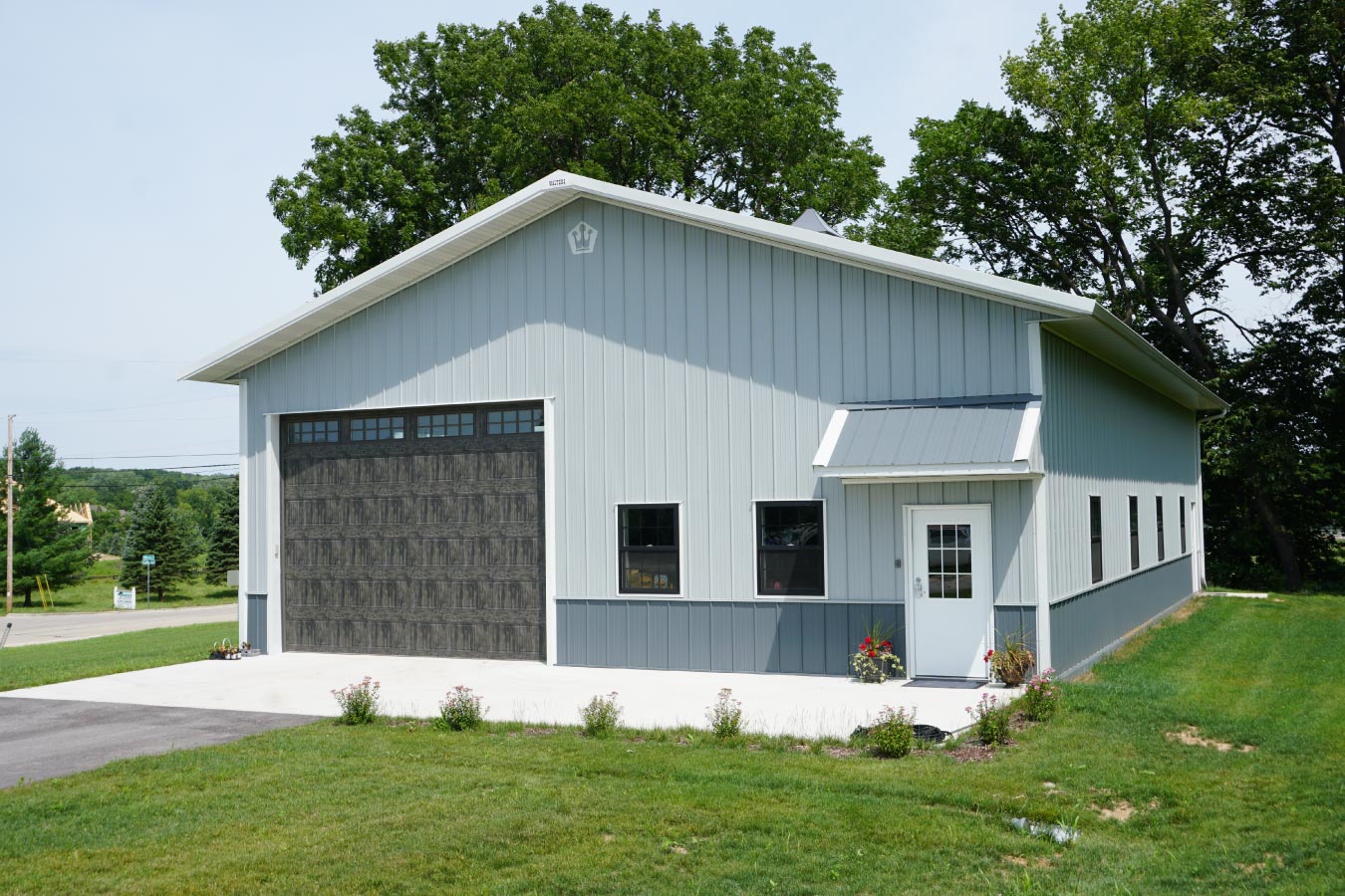 40x60 custom pole barn garage with white steel siding, charcoal wainscot, and oversized wood grain garage door