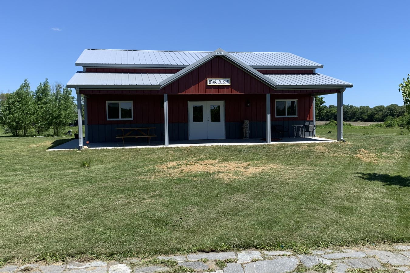 Front elevation of red garage with centered double entry doors, covered porch, and symmetrical post-frame design