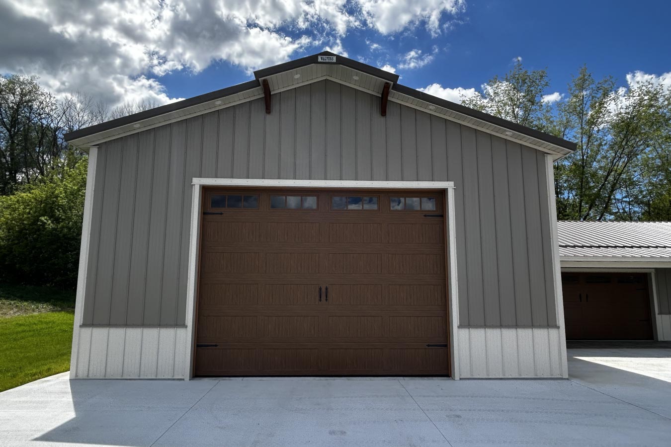 pole barn garage with oversized brown wood grain garage door and gray steel siding