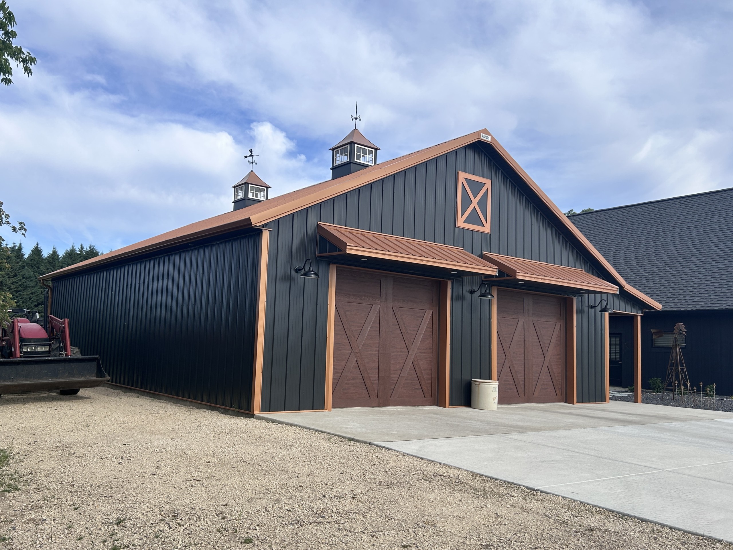 Pole barn garage with eyebrow overhangs above two overhead doors on a custom 36x50 metal garage by Walters Buildings