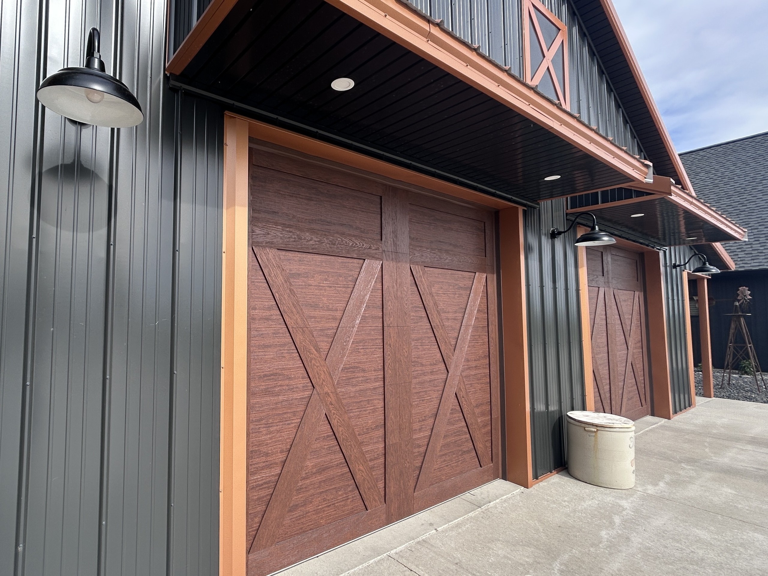 Close-up of Clopay Canyon Ridge overhead doors and gooseneck lighting on a custom pole barn garage by Walters Buildings