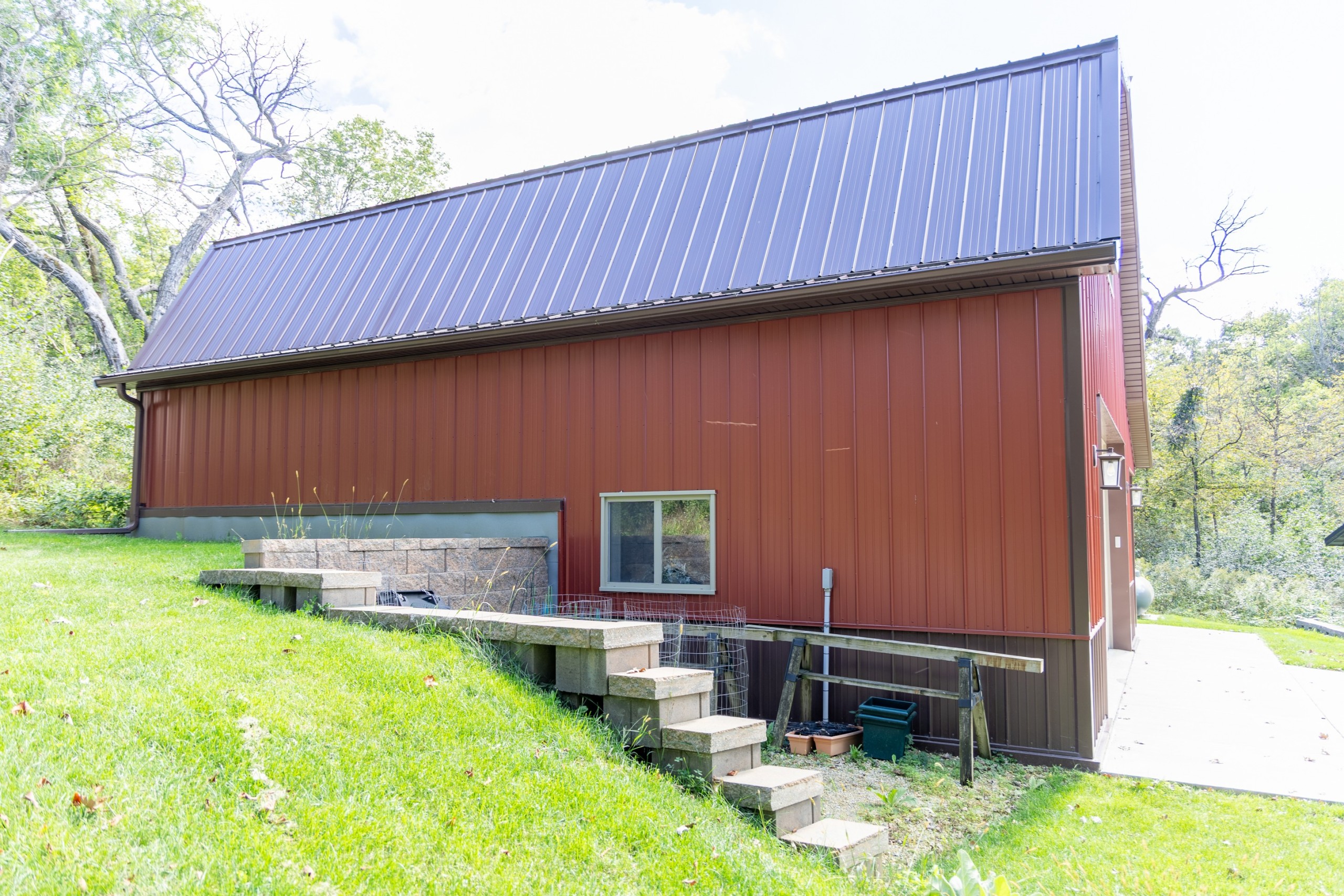 Side view of a two-story gambrel garage built into a hillside with a reinforced concrete retaining wall