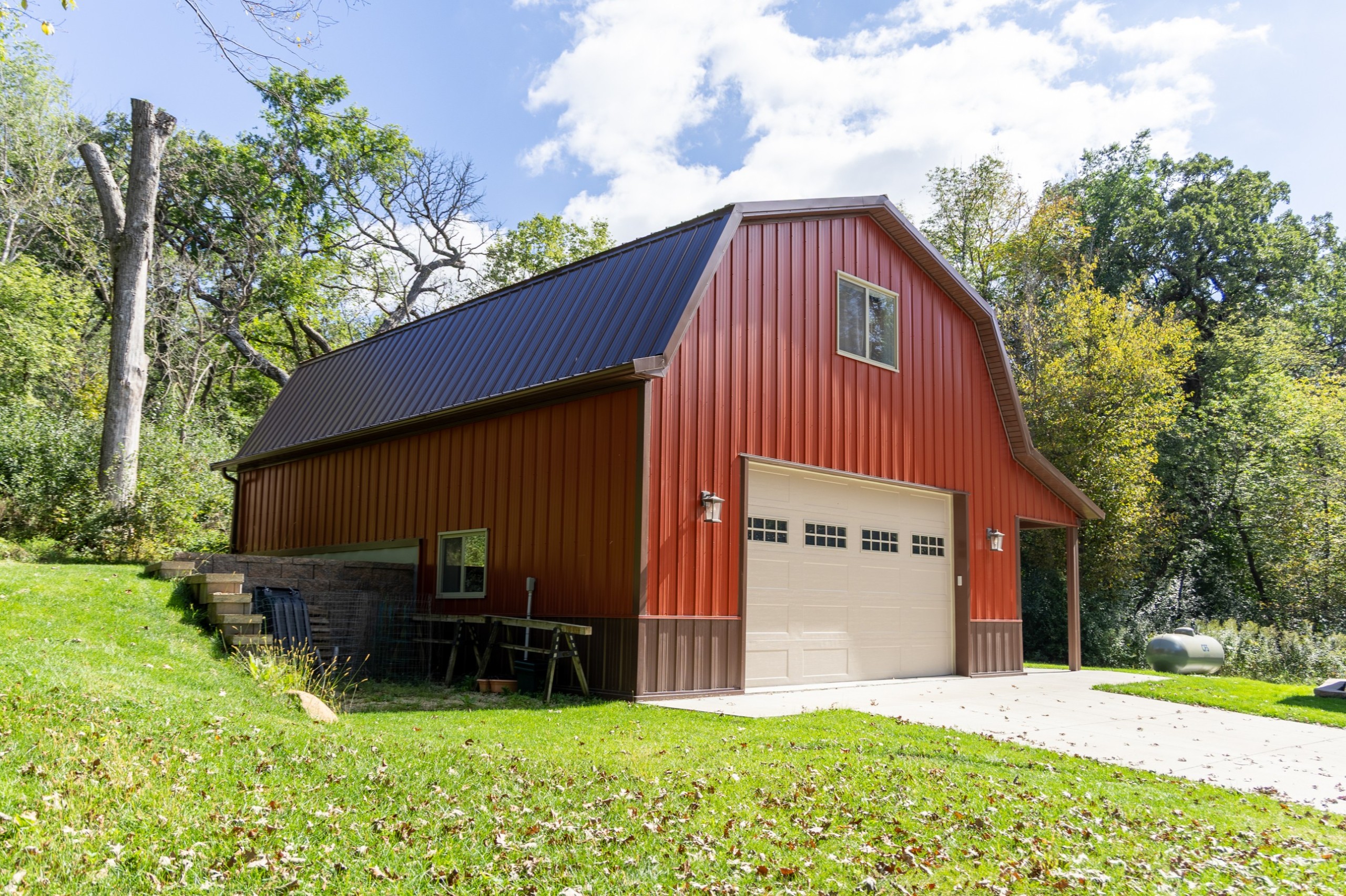 30' x 40' two-story gambrel pole barn garage with red steel siding, brown roof and trim, and a side porch in Nerstrand, Minnesota